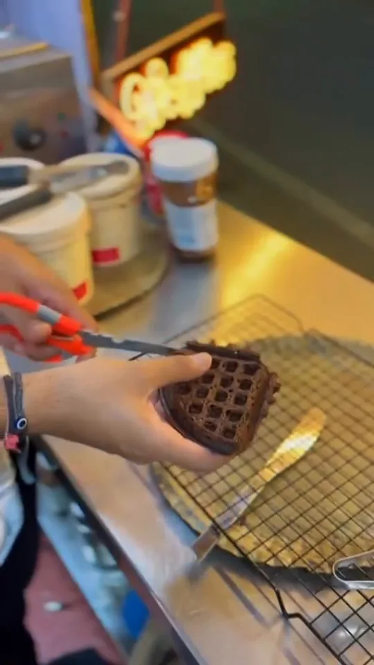 A waffle lifted off the iron with tongs